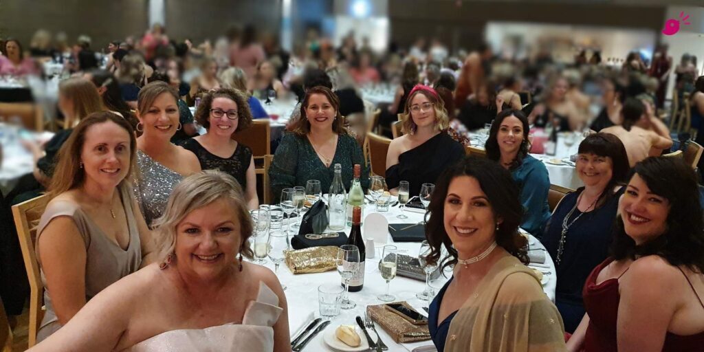 A group of women from Business Women Albury Wodonga seated around a dinner table at an event, smiling and enjoying an evening celebrating women in business and community over competition.